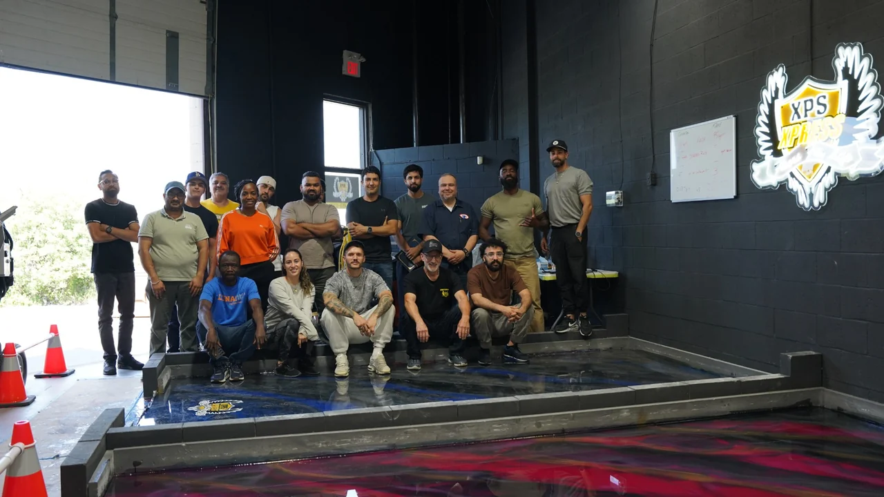 A training class poses together in the XPS Toronto workshop beside a finished metallic epoxy practice floor