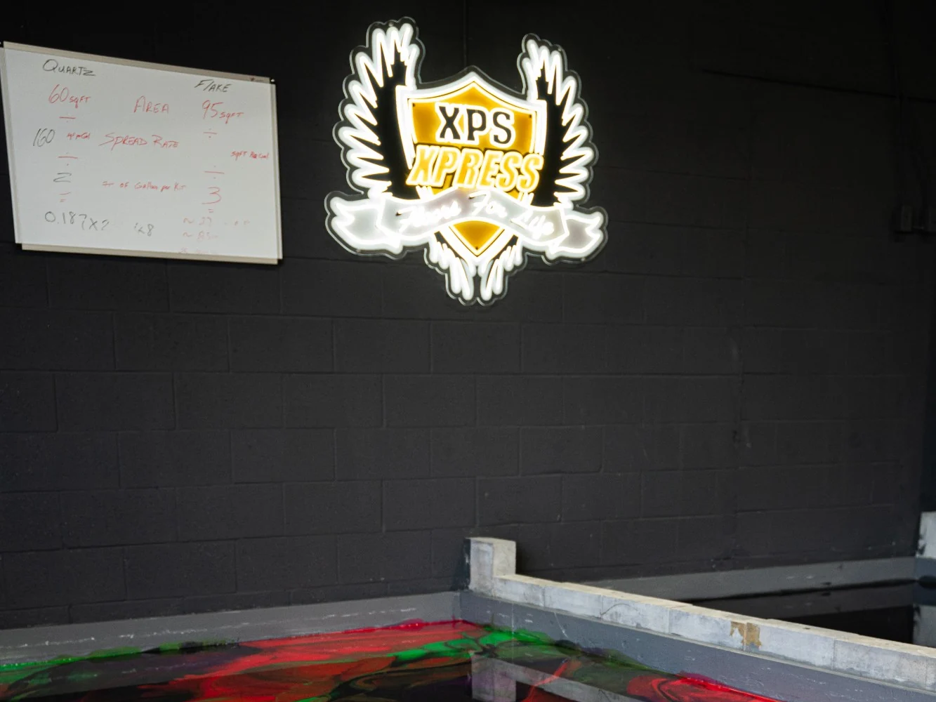 A whiteboard with quartz and flake area and spread-rate calculations beside the XPS Xpress sign