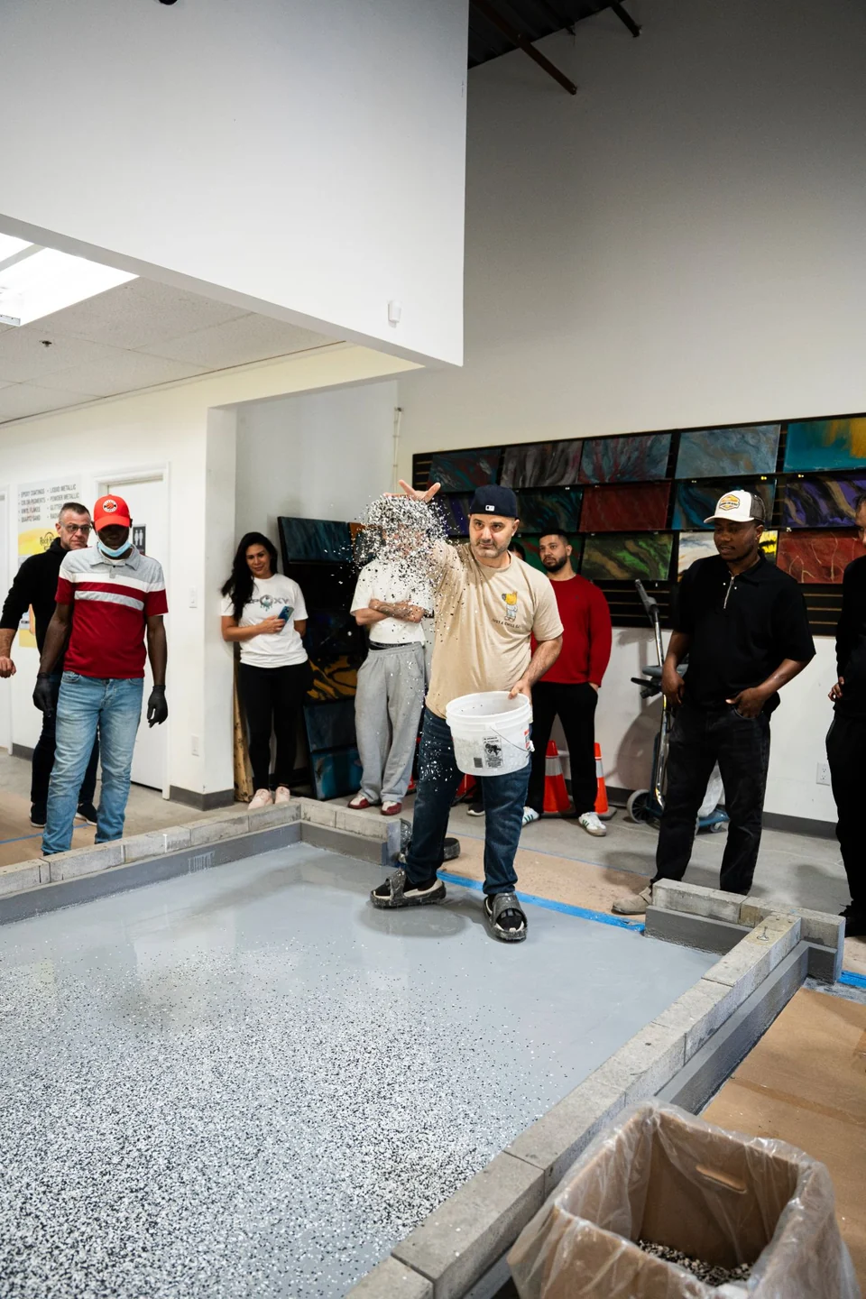 Vinyl flakes are broadcast by hand onto a wet base coat while the class watches