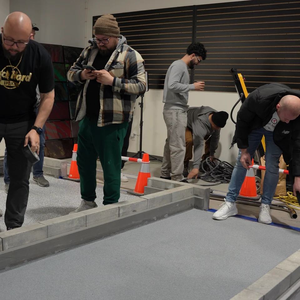 Students gather around a grey quartz practice floor in the XPS Toronto training workshop
