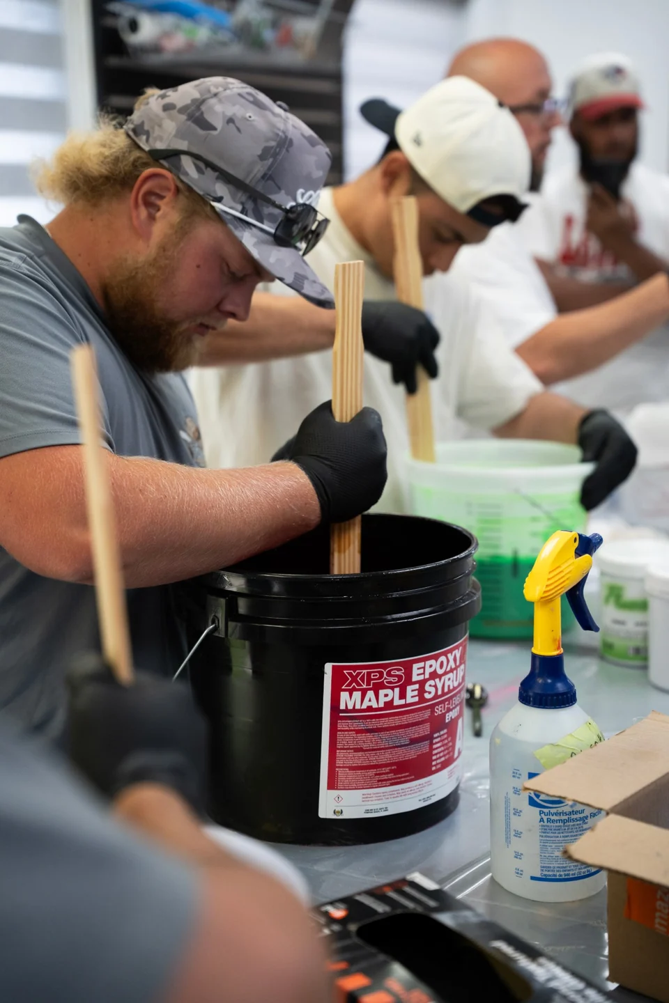 Students in gloves mix buckets of XPS epoxy at the mixing table